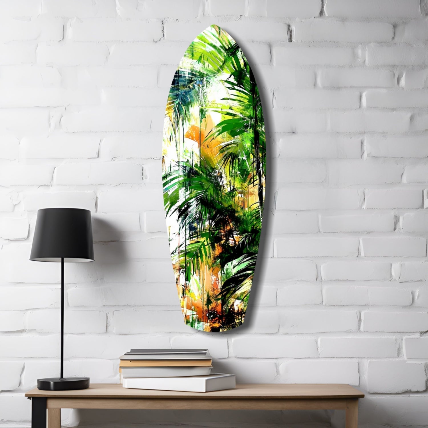 Oval tropical forest glass wall art with green palm leaves and golden-brown tones displayed above wooden desk with black lamp and stacked books.