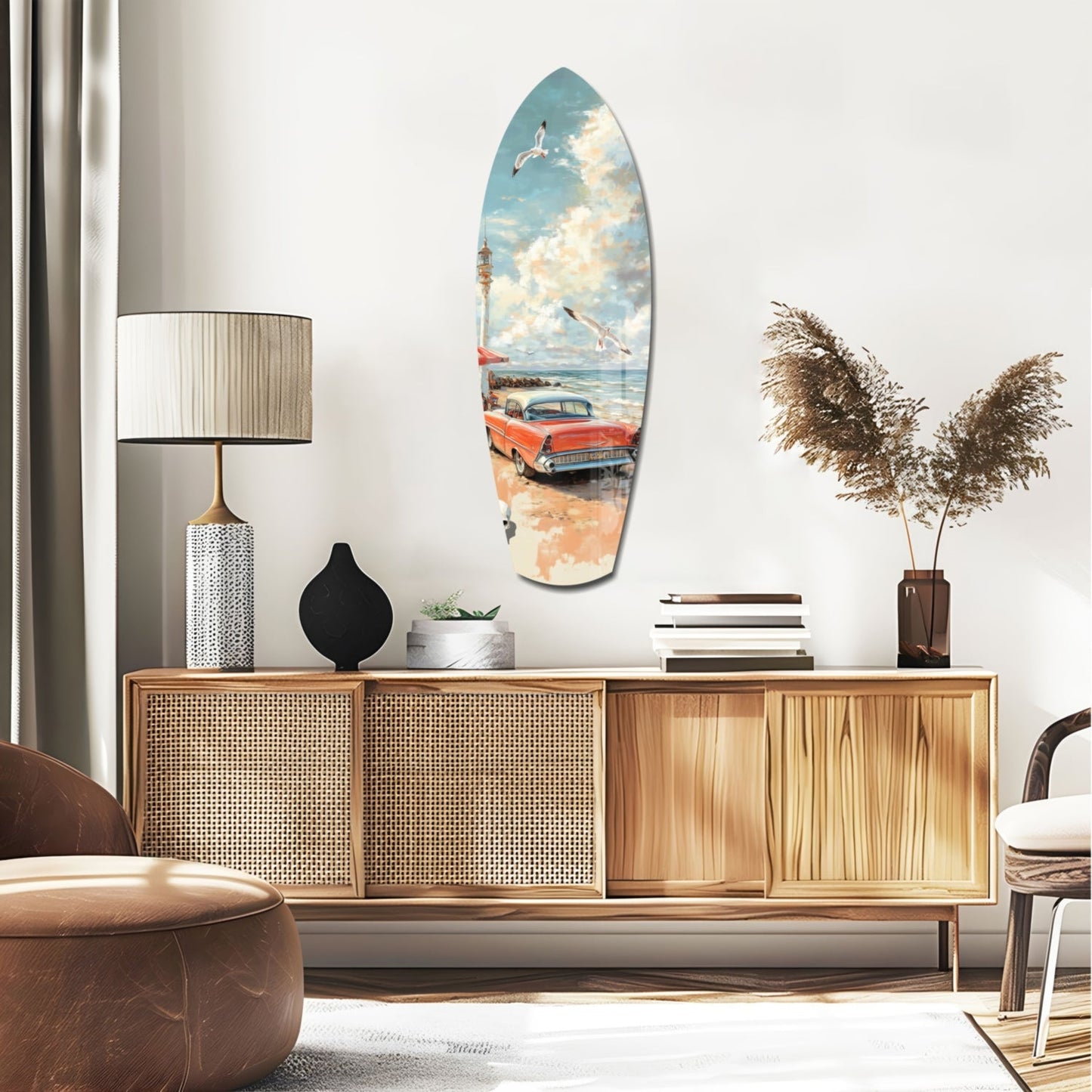 Surfboard-shaped glass wall art depicting a vintage red car on a beach with blue sky and clouds, displayed above a wooden credenza in a modern interior.