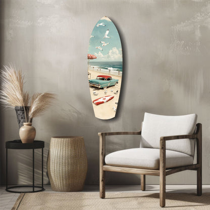 Surfboard-shaped glass wall art depicting a vintage beach scene with turquoise car, umbrella, and sailboat displayed in modern room setting.