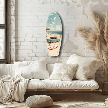 Surfboard-shaped glass art displaying vintage beach scene with turquoise car, sailboats, and red umbrella, hung on white brick wall above cream bedding.