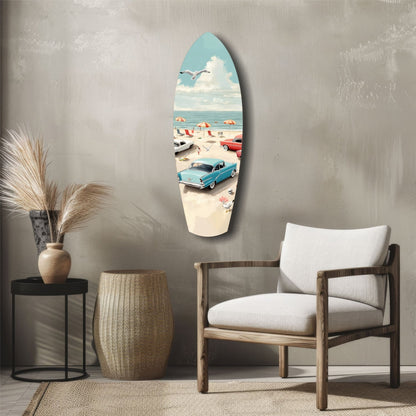 Surfboard-shaped glass wall art depicting vintage beach scene with blue car, umbrellas, and ocean, displayed in modern living room setting.