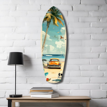 Surfboard-shaped glass wall art mounted on white brick, depicting vintage orange car on beach with palm tree, blue sky, and skull, displayed above wooden desk with lamp and books.