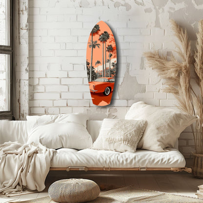 Surfboard-shaped glass wall art with orange vintage car and palm trees displayed above white bedding in minimalist bedroom.