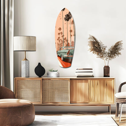 Surfboard-shaped glass art with vintage car and palm trees in peach and teal tones, displayed above mid-century wooden credenza.