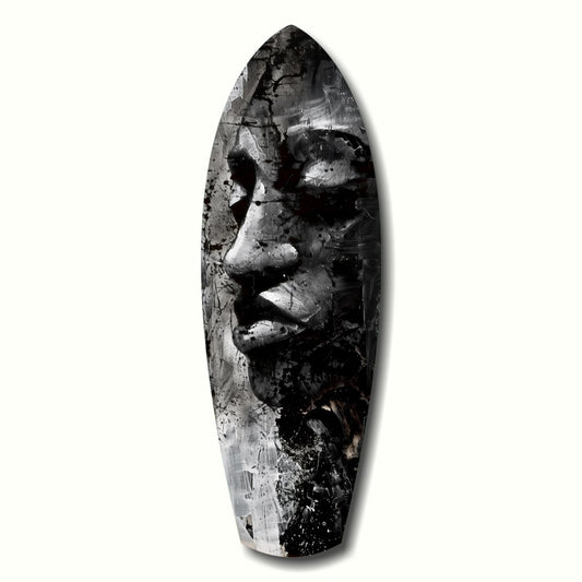 Black and white painted male face on elongated oval surfboard-shaped glass art against white background.