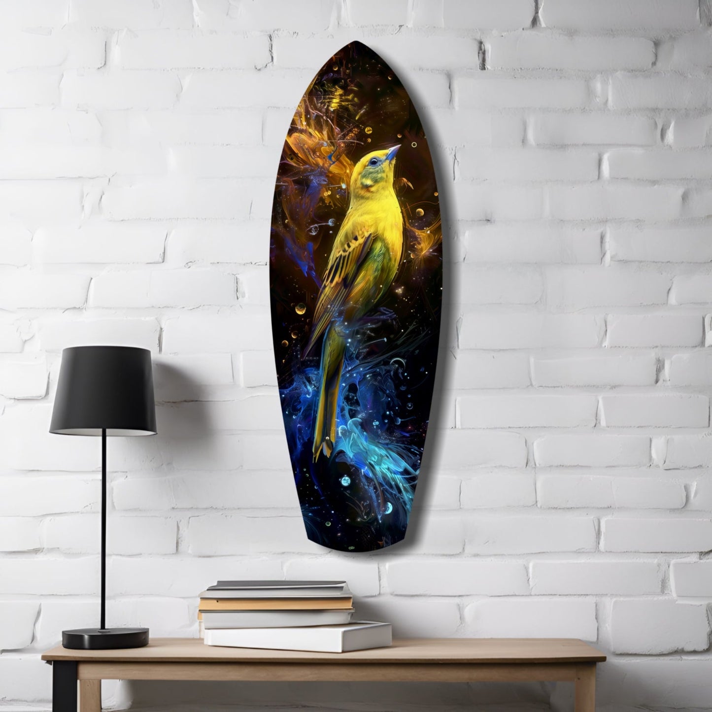 Elongated yellow bird glass wall art mounted on white brick above wooden desk with lamp and stacked books.