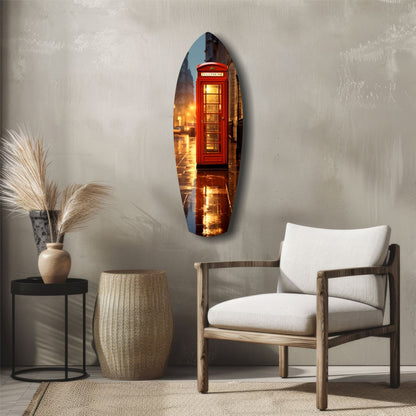 Oval glass wall art depicting a glowing red British telephone booth on a wet London street, displayed above a wooden chair in a minimalist interior.