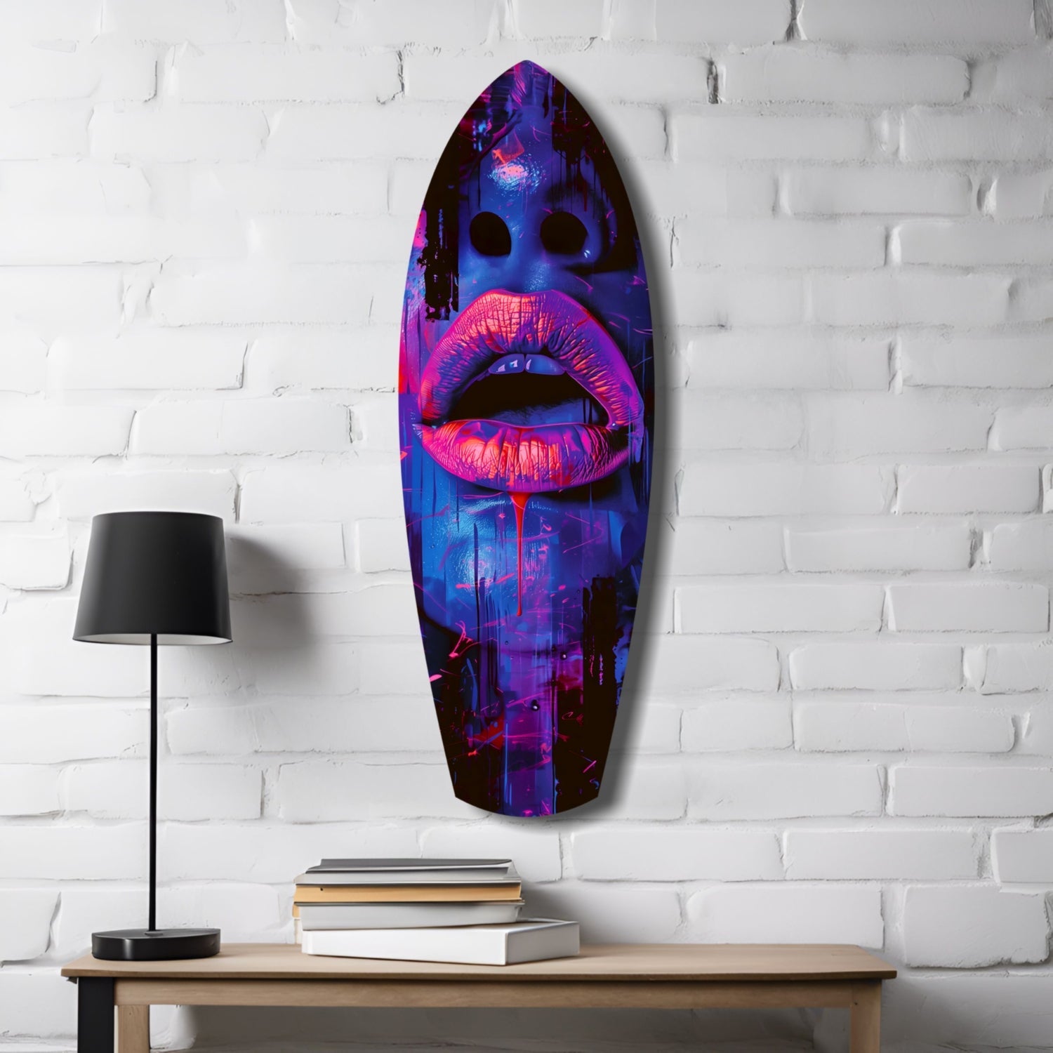 Neon pink lips on blue-purple gradient glass art panel mounted on white brick wall beside wooden desk with lamp and books.