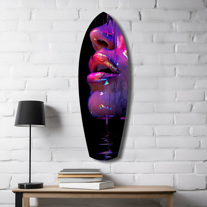 Oval glass wall art featuring vibrant neon pink, purple, and blue lips displayed above a wooden desk with lamp and books against white brick.