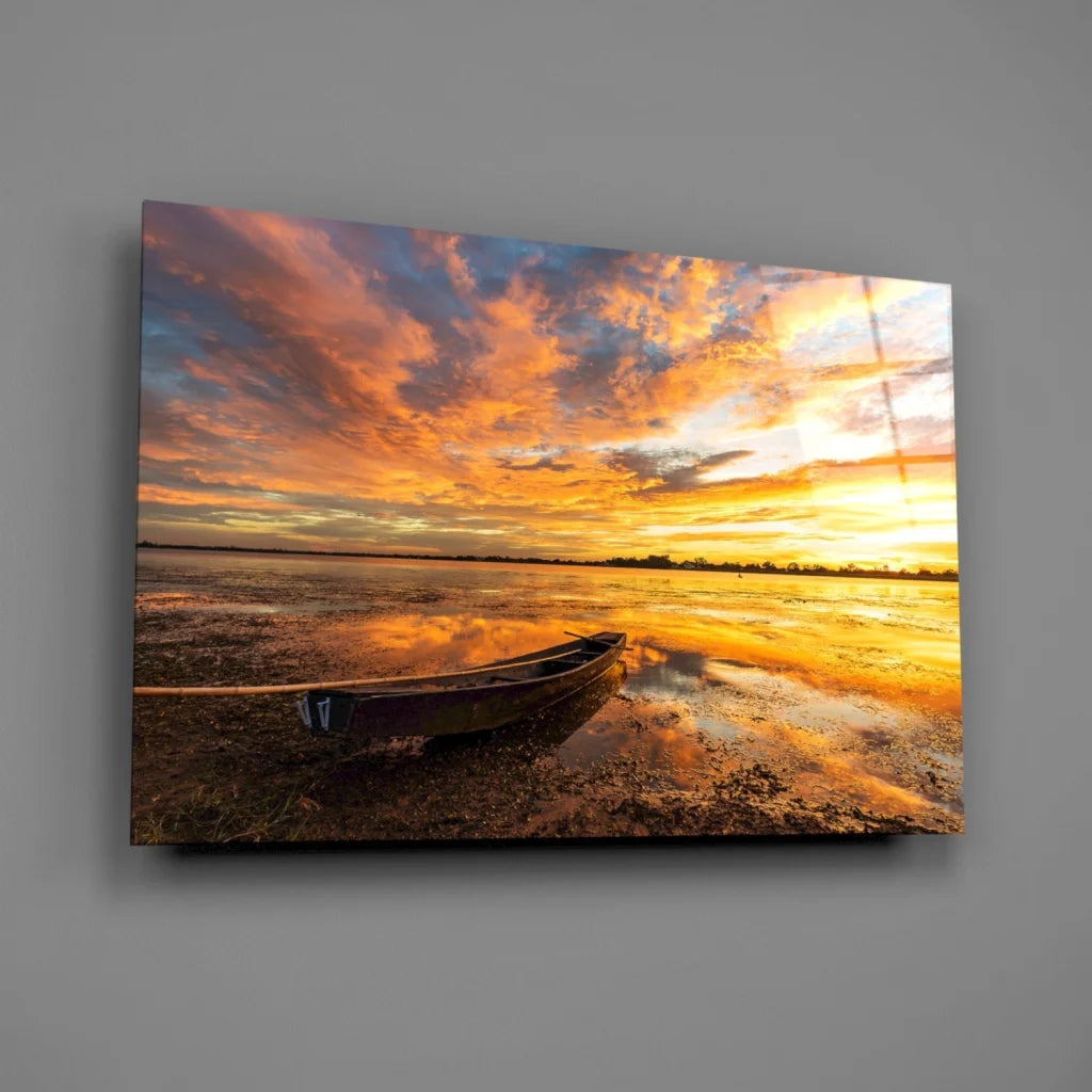 Vibrant sunset over water with lone canoe on shore, stunning glass wall art print