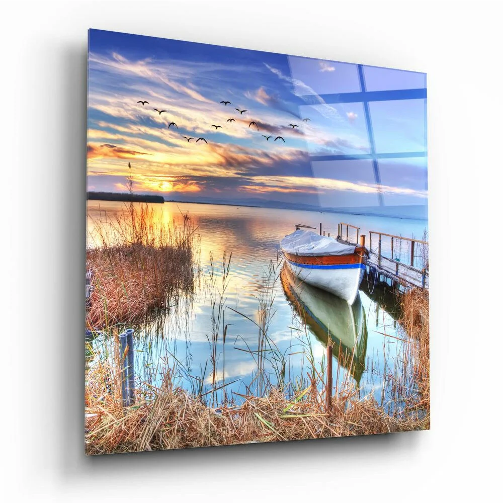 Serene sunset lake scene with white boat on glass wall art