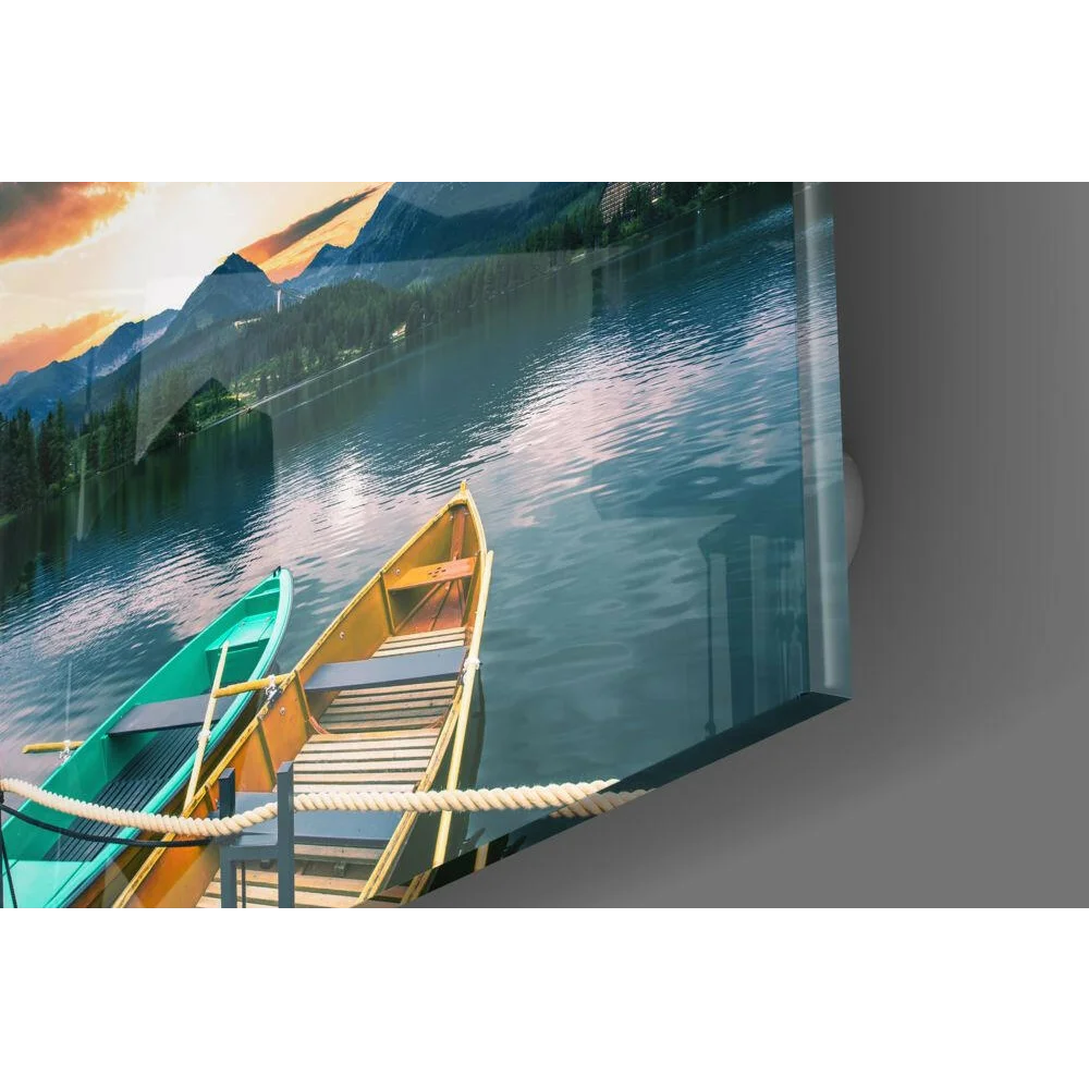 Teal and yellow canoes at sunset lake, glass wall art with mountains