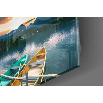 Teal and yellow canoes at sunset lake, glass wall art with mountains