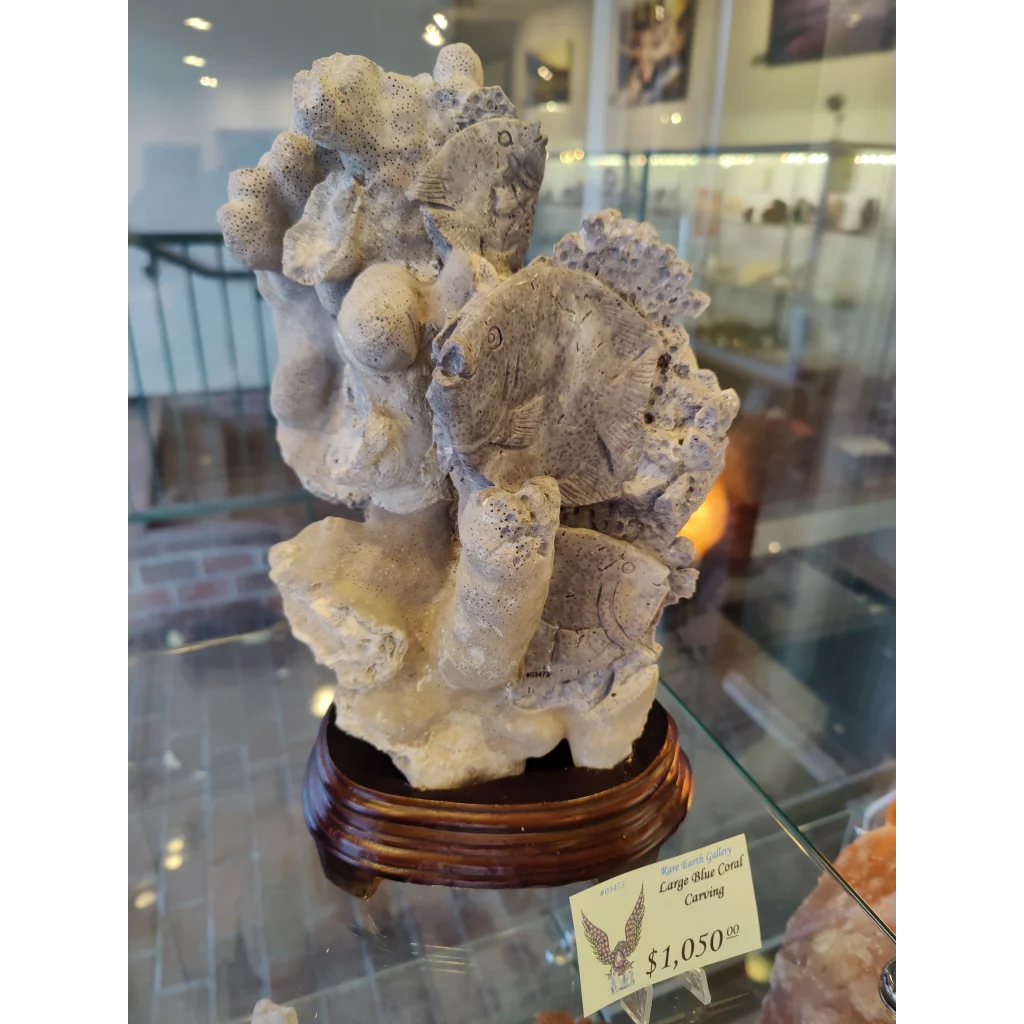 Large blue coral carving with intricate fish on polished wood base