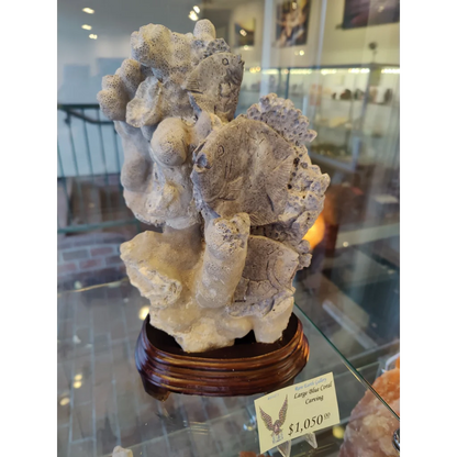 Large blue coral carving with intricate fish on polished wood base