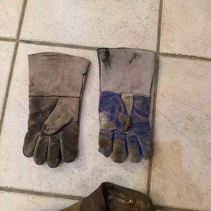 Worn leather work gloves with gray blue patch on back, from leather welding jacket coat