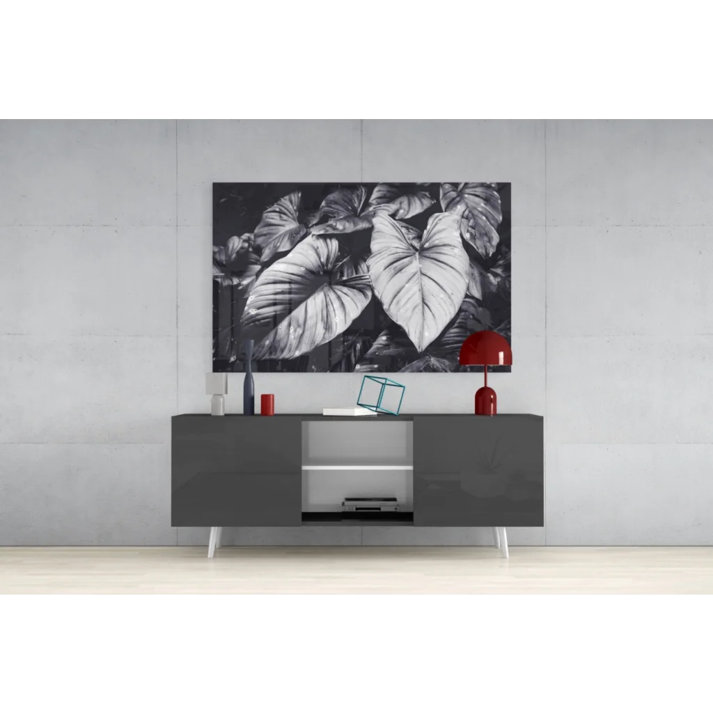 Black and white tropical leaves canvas wall art above gray sideboard