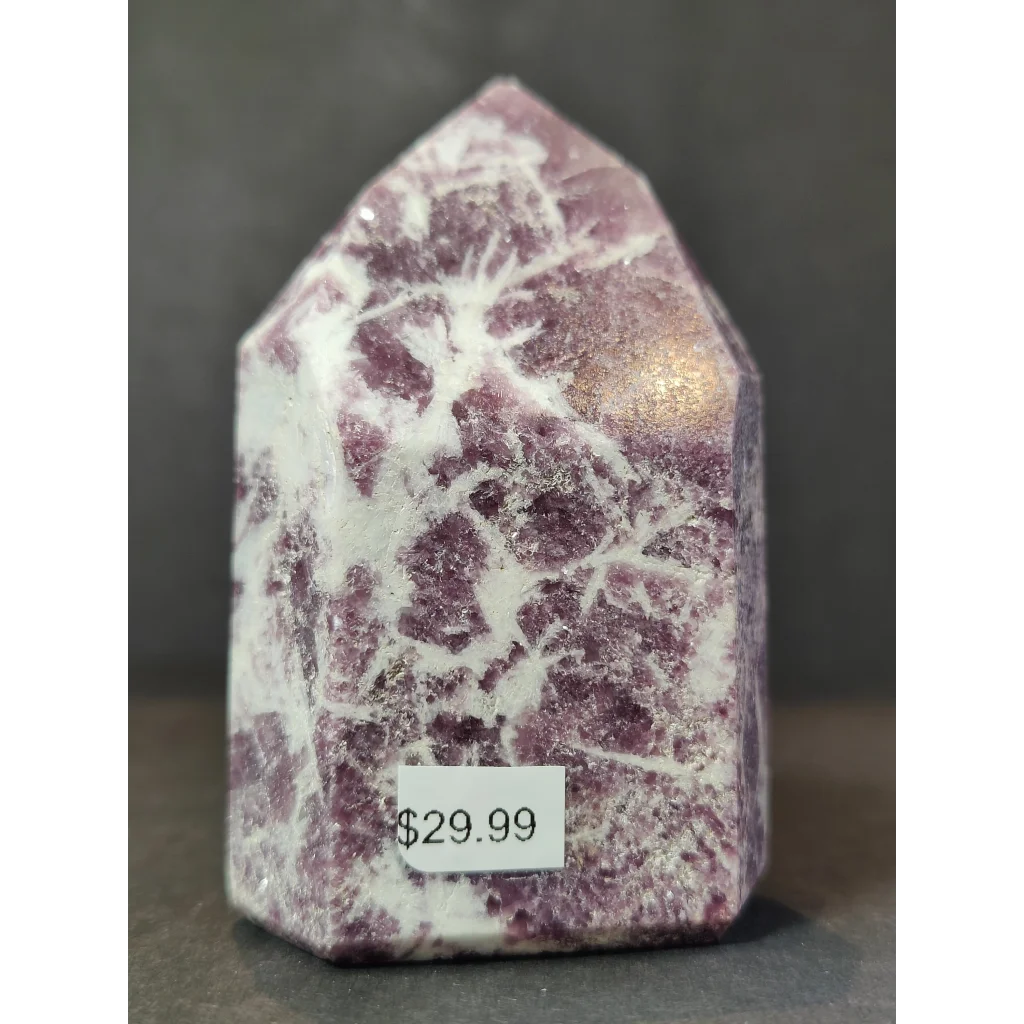 A polished purple and white lepidolite polished obelisk tower sculpture with a pointed house-shaped top