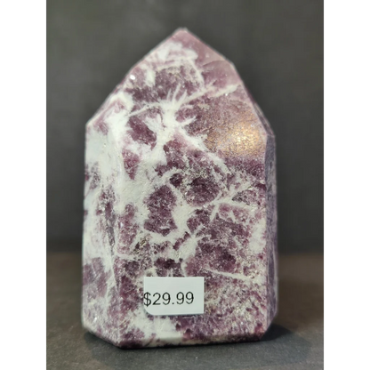 A polished purple and white lepidolite polished obelisk tower sculpture with a pointed house-shaped top
