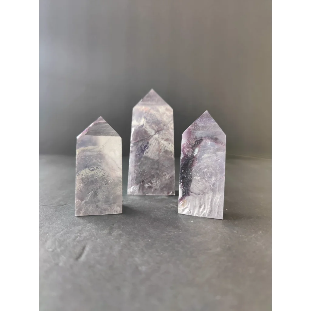 Three translucent quartz crystal lepidoite towers with gray and purple veining on clear glassy surfaces