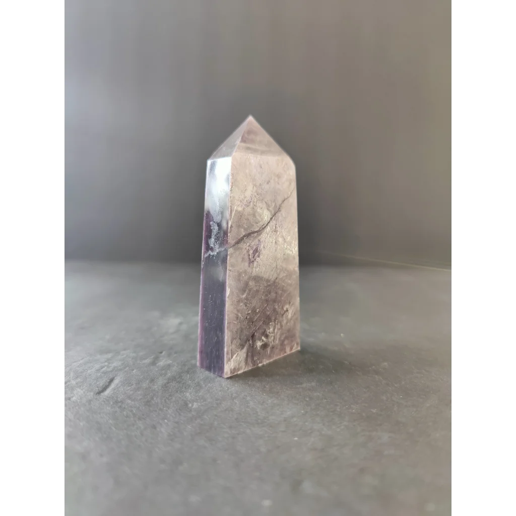 Lepidolite tower sculpture featuring a translucent faceted quartz point with subtle purple hue and natural veining