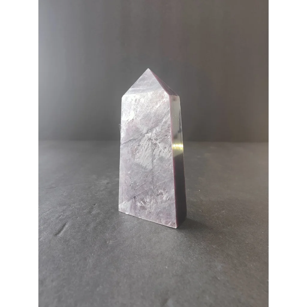 Lepidolite tower sculpture featuring a translucent pale lavender quartz crystal with a pointed top and faceted sides