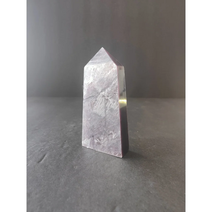 Lepidolite tower sculpture featuring a translucent pale lavender quartz crystal with a pointed top and faceted sides