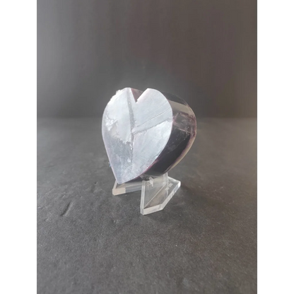 A translucent heart-shaped lepidolite crystal sculpture with a smooth polished surface and subtle internal reflections