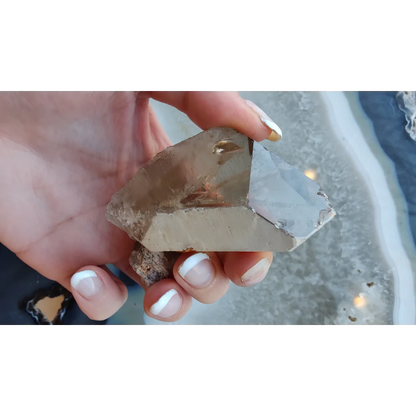 Hand holding lodalite included smoky quartz crystal from Brazil