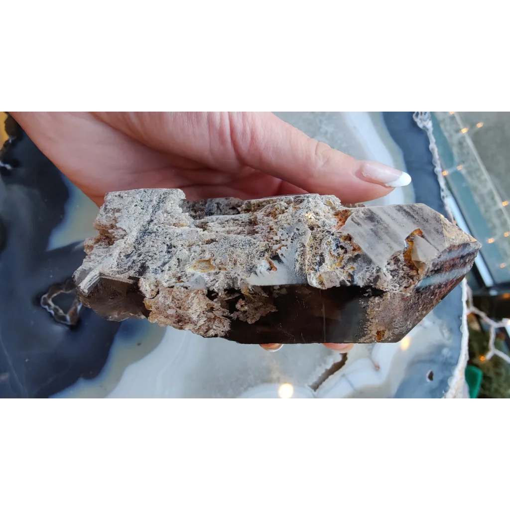 Hand holding lodalite included smoky quartz crystal from Brazil