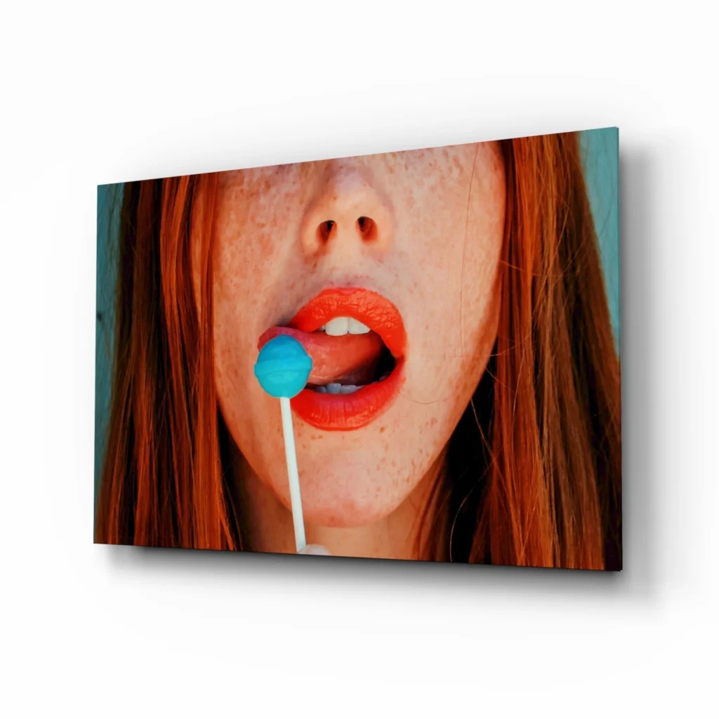 Pop art redhead glass wall art: freckled woman with orange lips and blue lollipop