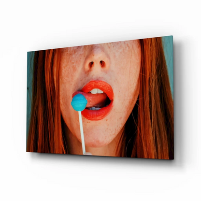 Pop art redhead glass wall art: freckled woman with orange lips and blue lollipop