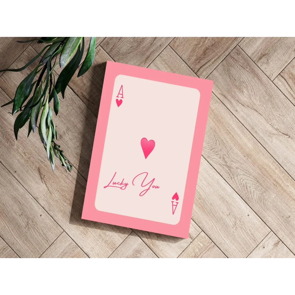 Lucky You Pink Heart Ace playing card on wood surface