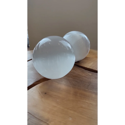 Two luminous Moroccan selenite spheres on wood, 8cm pure crystal energy