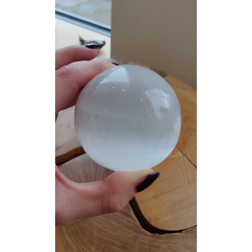 Hand holding luminous 8cm Moroccan selenite sphere