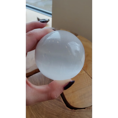 Hand holding luminous 8cm Moroccan selenite sphere