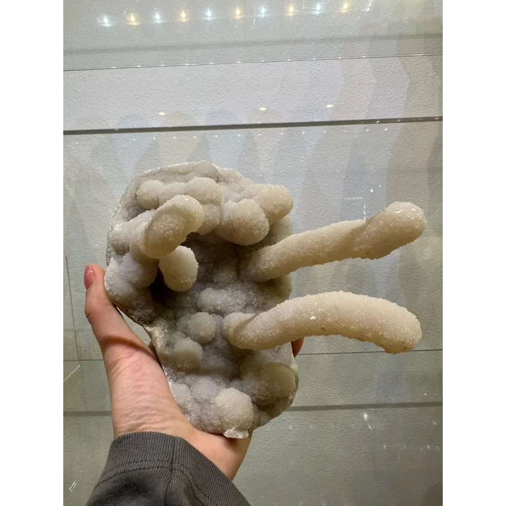 Hand holding medium chalcedony stalactite geode from India