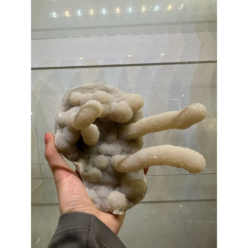 Hand holding medium chalcedony stalactite geode from India
