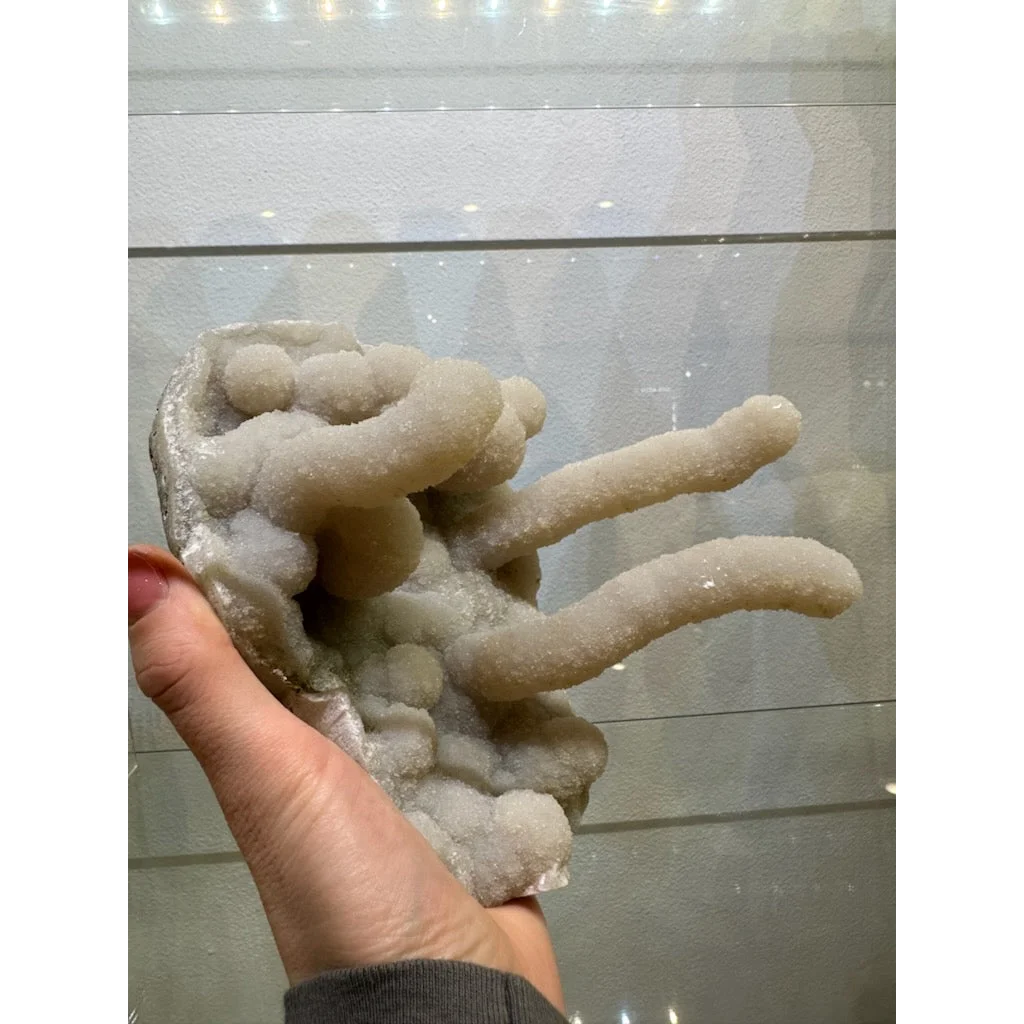 Medium chalcedony stalactite hand geode from India with pale translucent crystals