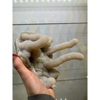 Medium chalcedony stalactite hand geode from India with pale translucent crystals