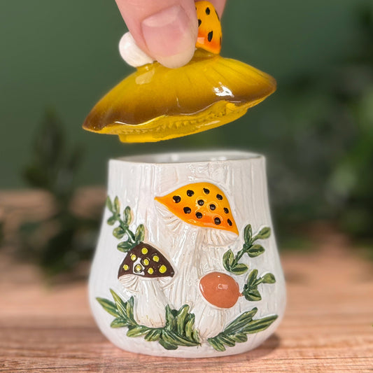 Hand lifting the mushroom lid off the mushroom canister trinket box