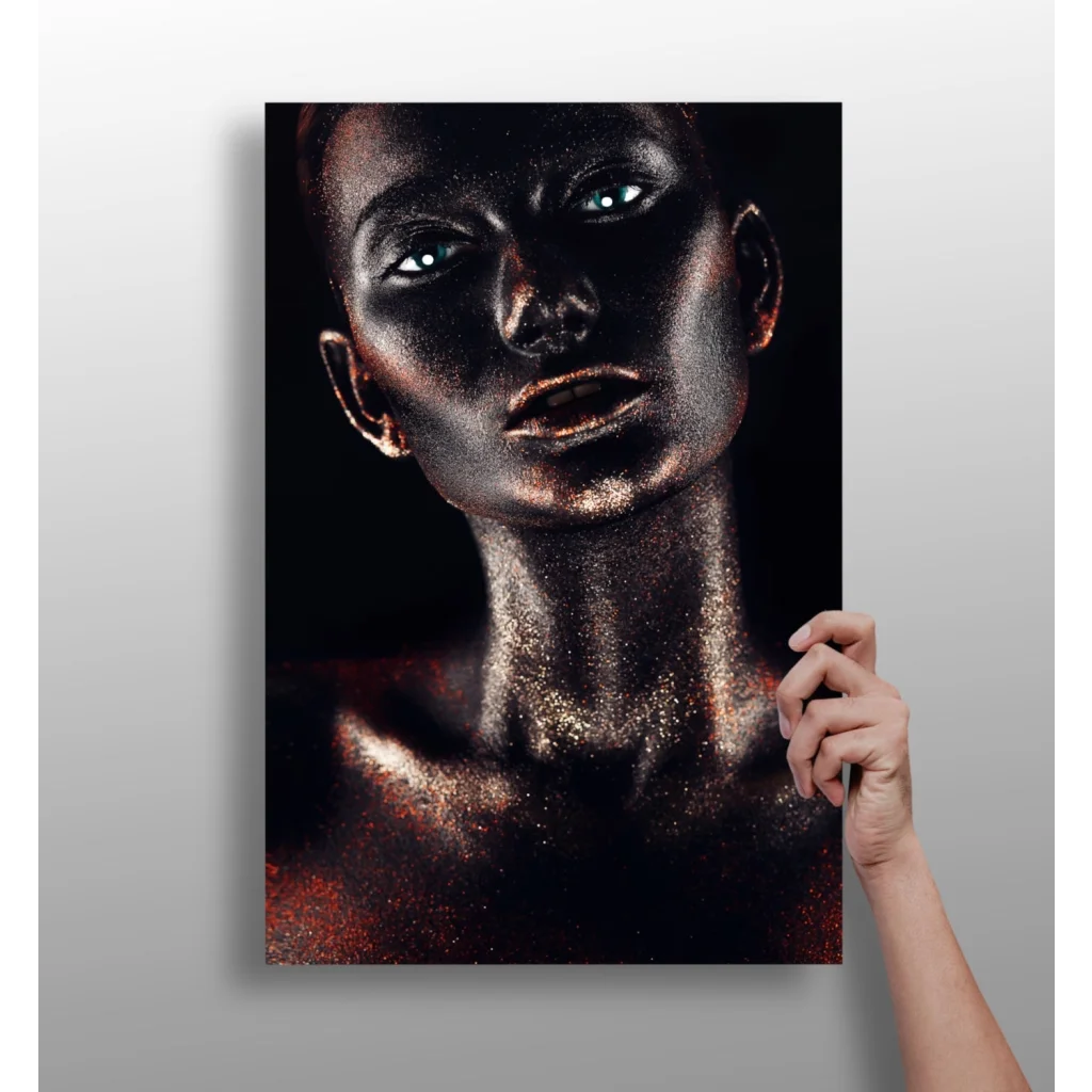 Hand holding black-and-gold glitter portrait of woman with metallic skin and glowing blue eyes canvas print