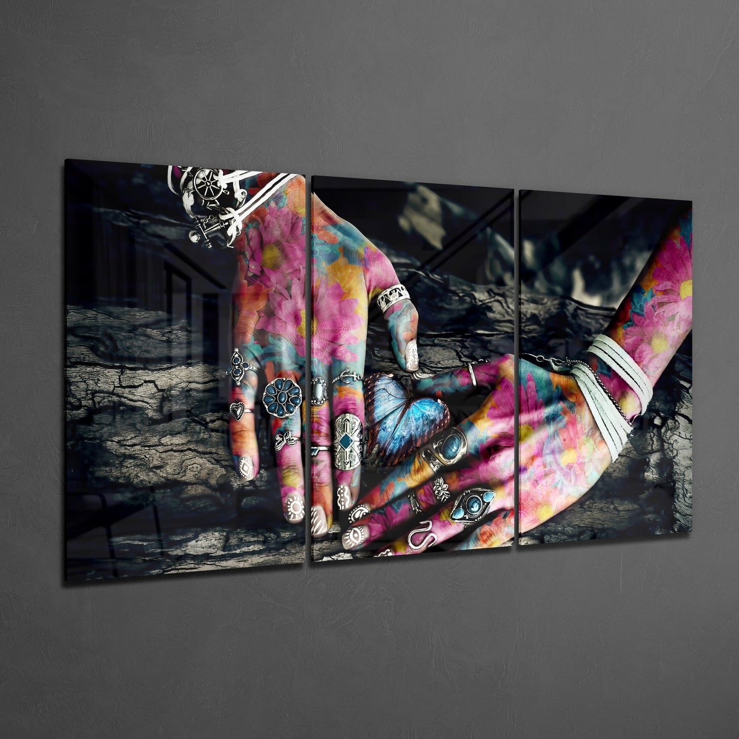 Three-panel glass wall art displaying vibrant tie-dye hands with silver rings against a dark textured background.