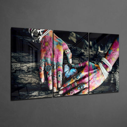 Three-panel glass wall art displaying vibrant tie-dye hands with silver rings against a dark textured background.