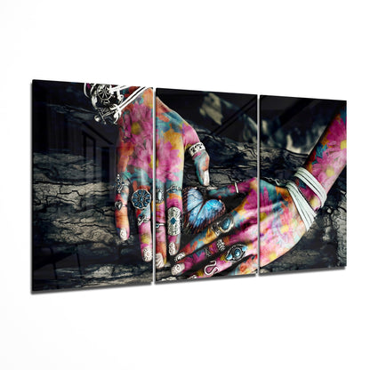 Three-panel glass wall art displaying tattooed hands with vibrant pink, yellow, and blue tie-dye patterns against a dark industrial background.