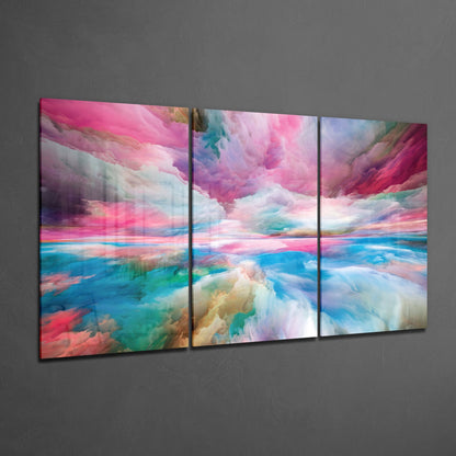 Three-panel glass wall art displaying a surreal landscape with pink, blue, and turquoise clouds reflected in water, mounted on gray wall.