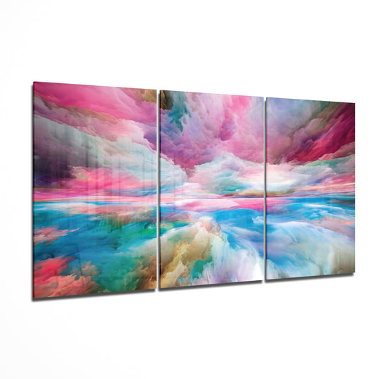 Three-panel glass wall art displaying a dreamy landscape with pink, blue, and turquoise clouds reflecting over water, displayed at an angle.
