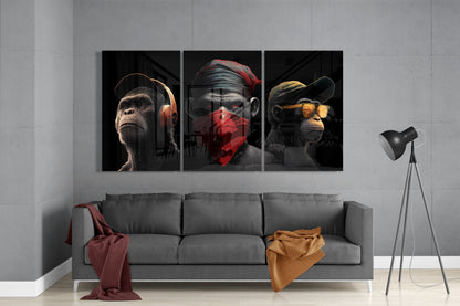 Three glass wall art panels depicting anthropomorphic monkeys wearing headphones, red bandana, and yellow sunglasses displayed above gray sofa in modern interior.