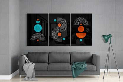 Modern living room with gray sofa displaying three black glass panels featuring geometric designs in turquoise and orange circles above.