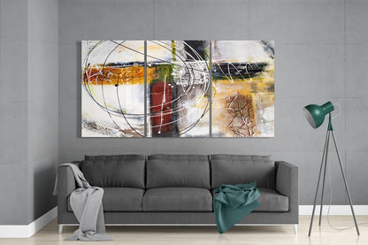 Three-panel abstract glass wall art with circular line designs, ochre, red, and cream tones, installed above gray sofa in modern living room.